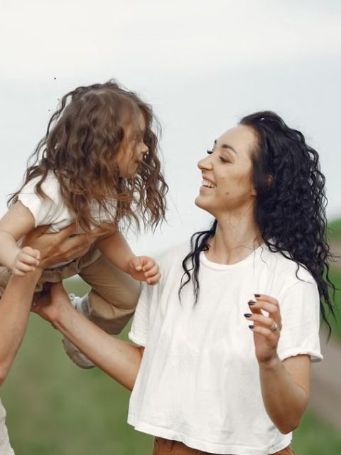 A joyful family moment outdoors with parents playing with their daughter.
