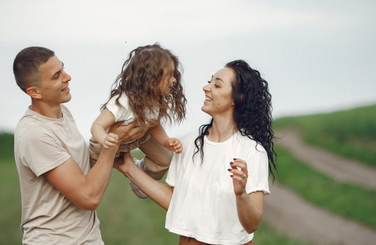 A joyful family moment outdoors with parents playing with their daughter.